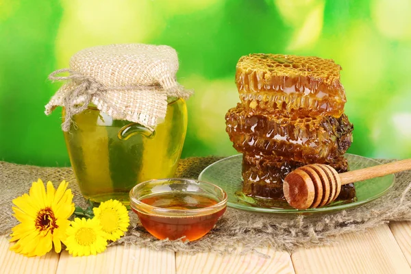 Tarro de miel y panal sobre mesa de madera sobre fondo natural —  Fotos de Stock