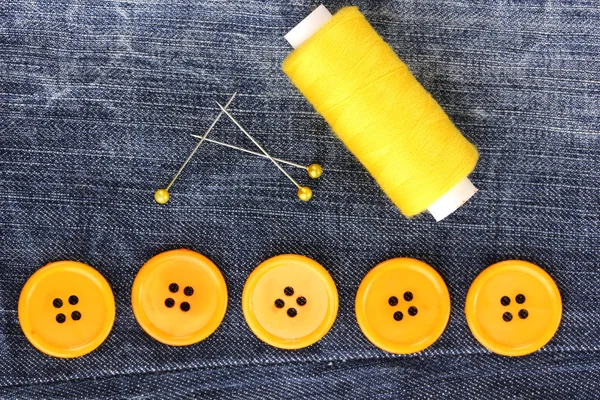 Colorful sewing buttons with thread on jeans closeup — Stock Photo, Image