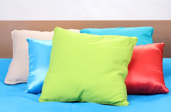 Jasne poduszki na łóżku na białym tle — Zdjęcie stockowe