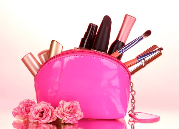 Borsa per trucco con cosmetici e pennelli su sfondo rosa — Foto Stock