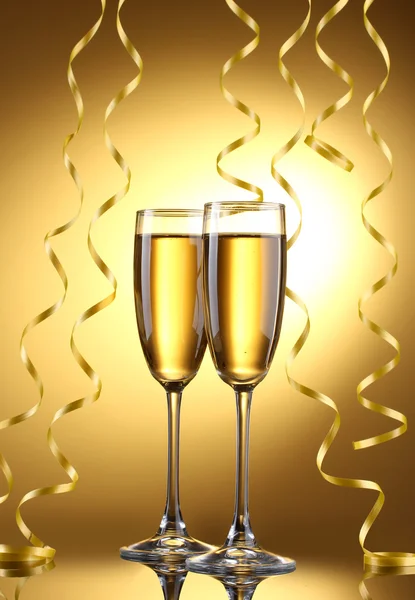 Glasses of champagne and streamer on yellow background — Stock Photo, Image
