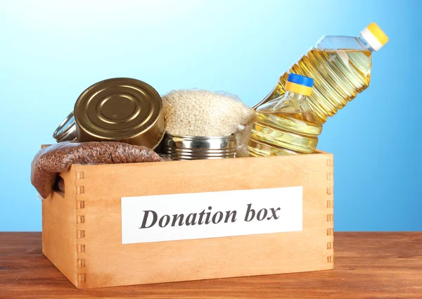 Spendenbox mit Lebensmitteln auf blauem Hintergrund in Großaufnahme — Stockfoto