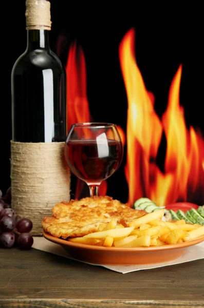 Roast chicken cutlet with french fries, glass of wine on fire background — Stock Photo, Image
