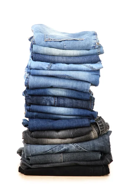 Många jeans staplade i en hög isolerad på vit — Stockfoto