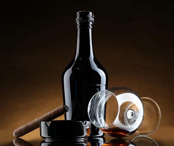 Flasche und Glas Schnaps und Zigarre auf braunem Hintergrund — Stockfoto
