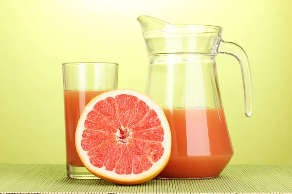 Grapefruitsap en grapefruit op bamboe mat op groene achtergrond — Stockfoto
