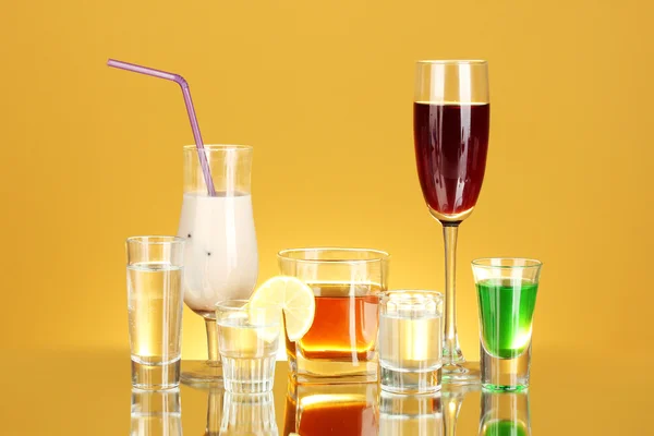 Širokou nabídku alkoholických nápojů na žlutém podkladu — Stock fotografie