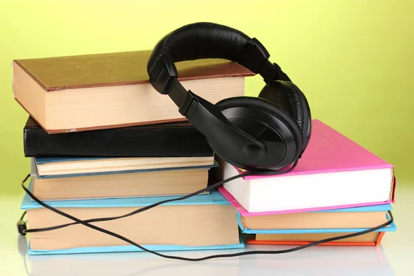 Headphones on books on green background — Stock Photo, Image