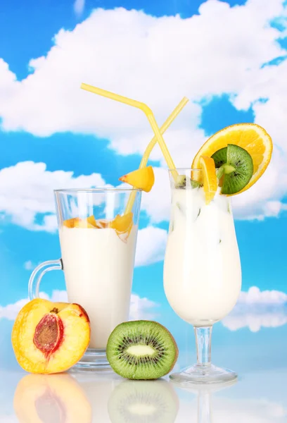 Délicieux milk shake avec des fruits sur la table sur fond de ciel — Photo
