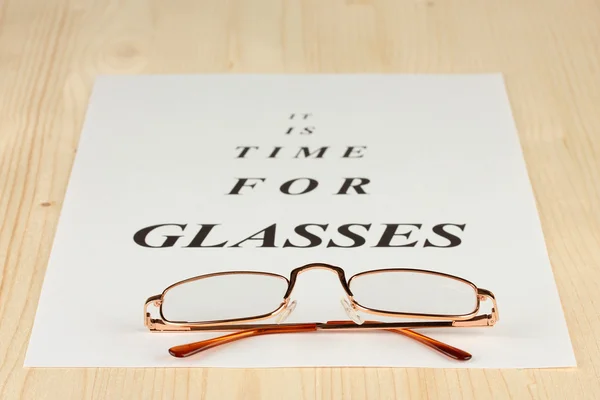 Zrak testovací graf s brýlemi na detail dřevěné pozadí — Stock fotografie