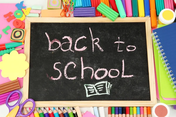 Οι λέξεις 'επιστροφή στο σχολείο", γραμμένο με κιμωλία για το μικρό σχολείο γραφείο με διάφορες σχολείο προμήθειες close-up — Φωτογραφία Αρχείου