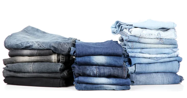 Många jeans staplade i en isolerad på vita högar — Stockfoto