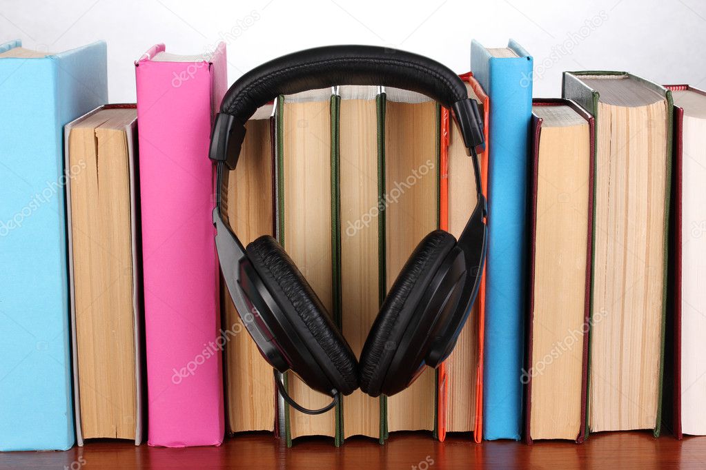 Headphones on books on wooden table on white background