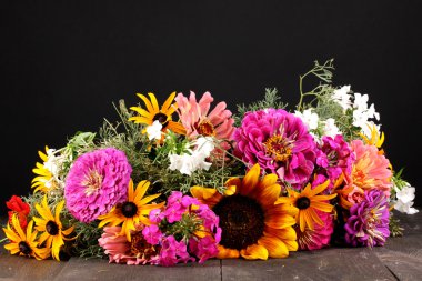 Beautiful bouquet of bright flowers on wooden table on black background clipart