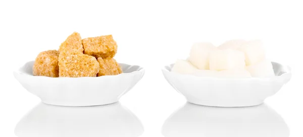 Cubos de açúcar castanho e branco em pires isolados sobre branco — Fotografia de Stock