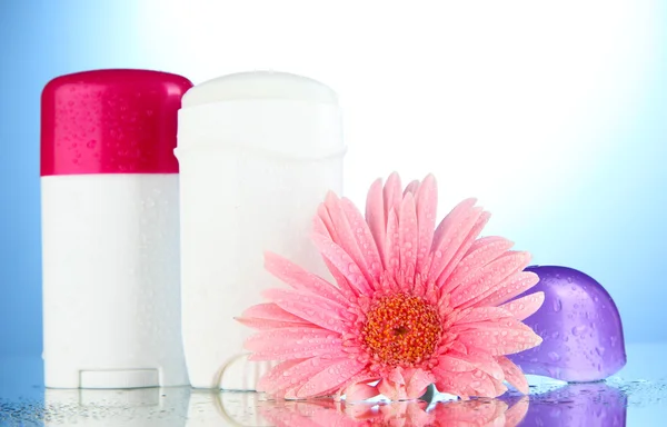 Deodorant Flaschen mit Blume auf blauem Hintergrund — Stockfoto