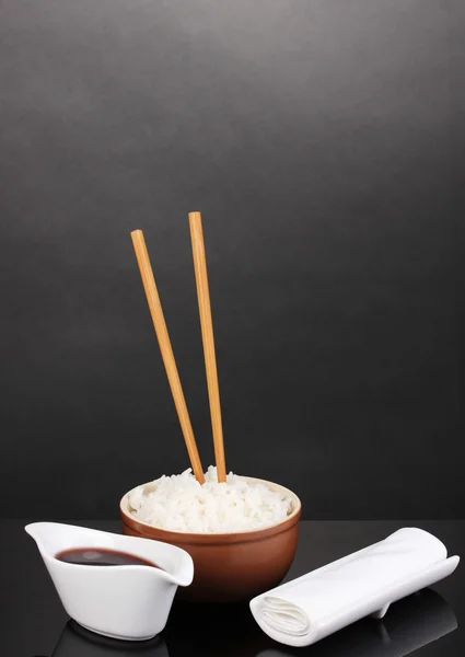 Bowl of rice and chopsticks on grey background — Stock Photo, Image