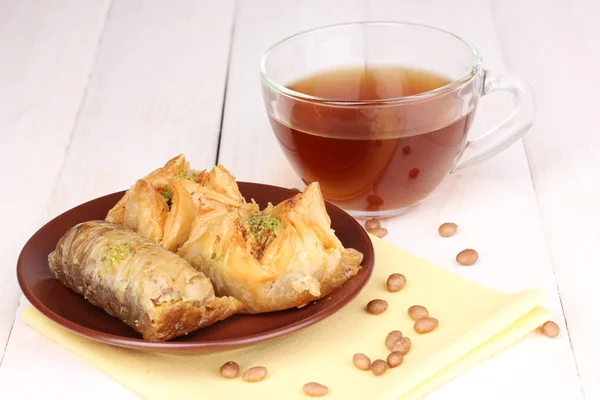 stock image Sweet baklava on plate with tea on wooden background