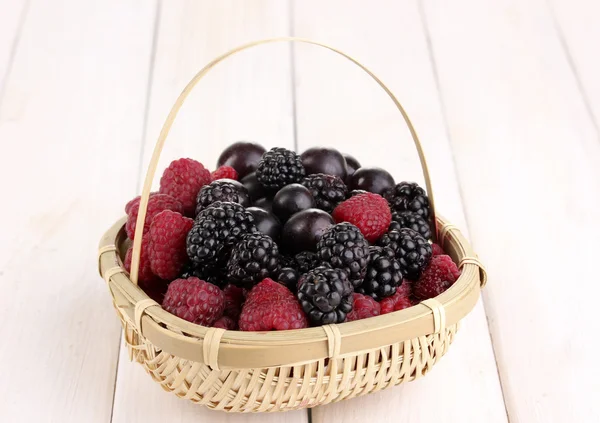 Ripe raspberries and brambles in basket on wooden table — Stock Photo, Image