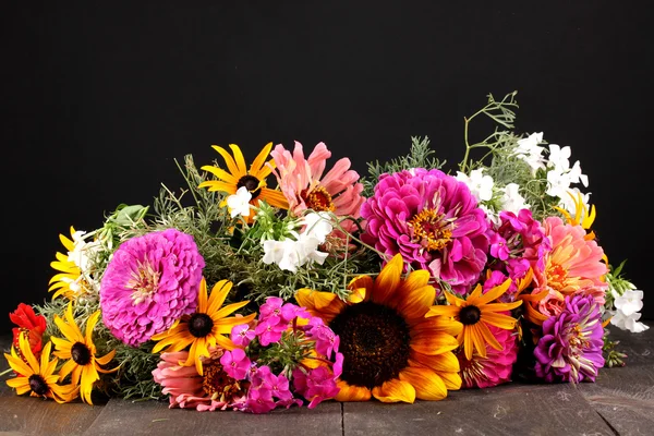 stock image Beautiful bouquet of bright flowers on wooden table on black background