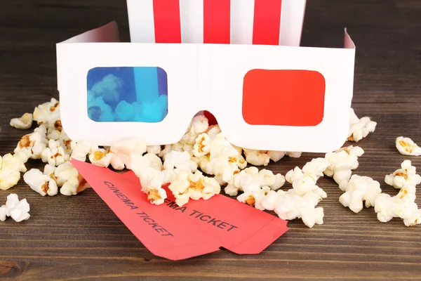 Popcorn med glasögon och biljetter på träbord på grå bakgrund — Stockfoto