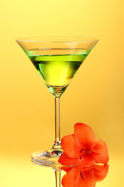 Verre avec cocktail et bourgeon de gladiole sur fond jaune gros plan — Photo