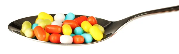 Píldoras de colores en cuchara sobre fondo blanco de cerca — Foto de Stock