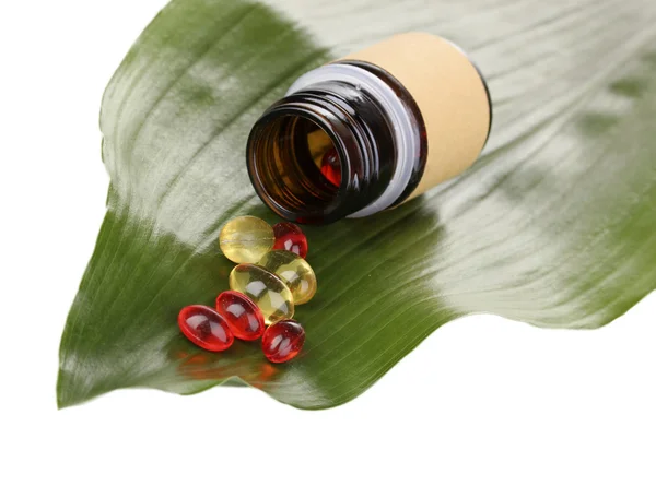 Tabletter på gröna blad med flaska isolerad på vit — Stockfoto