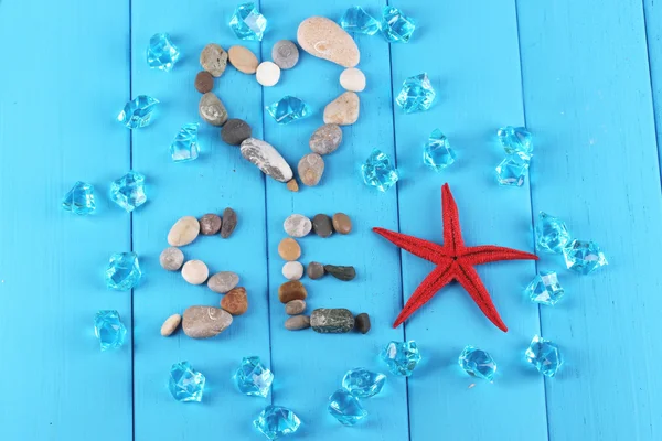 A palavra mar e decoração de conchas close-up na mesa de madeira azul — Fotografia de Stock
