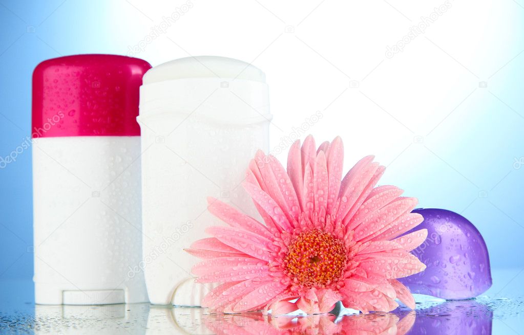 Deodorant botttles with flower on blue background