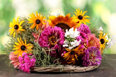 Beautiful bouquet of bright flowers on wooden table on nature background clipart