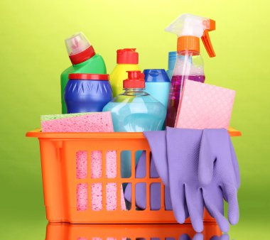 Basket with cleaning items on green background clipart