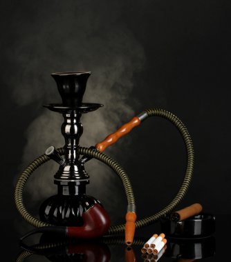 Smoking tools - a hookah, cigar, cigarette and pipe on black background clipart