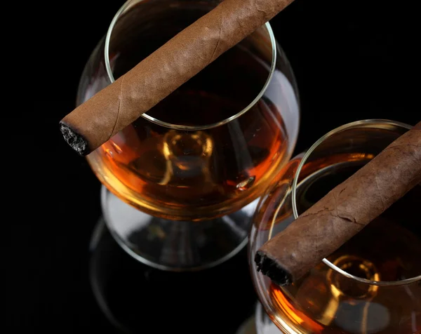 Dos copas de brandy y cigarros sobre fondo negro —  Fotos de Stock