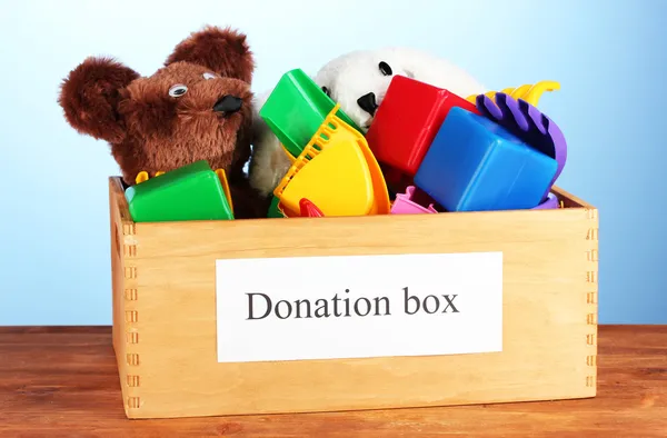 Donatie box met kinderen speelgoed op blauwe achtergrond close-up — Stockfoto