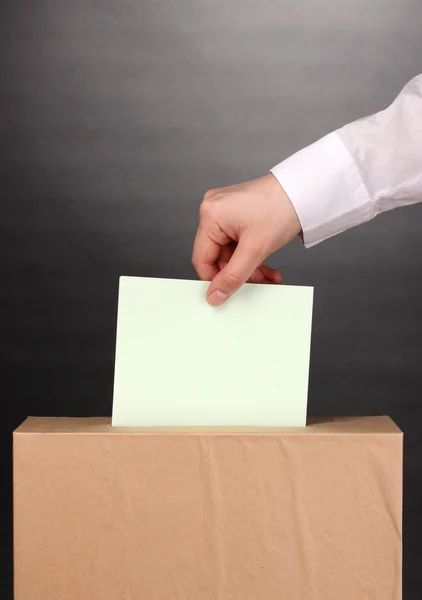 Hand with voting ballot and box on grey background — Stock Photo, Image