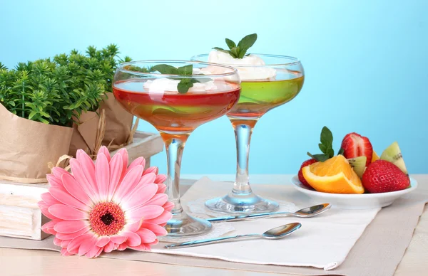 Fruchtgelee in Gläsern und Obst auf dem Tisch auf blauem Hintergrund — Stockfoto