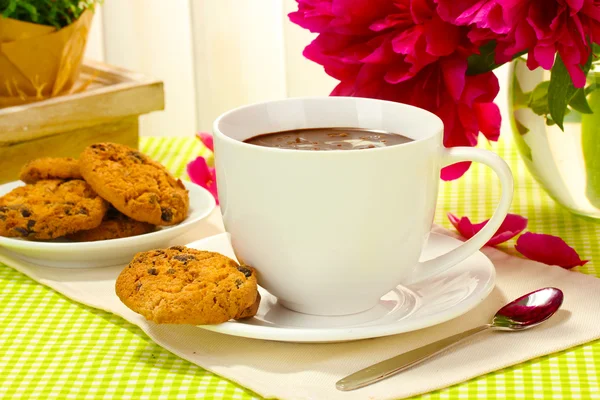 Cup hot chocolate, cookies and flowers on table in cafe — Stock Photo, Image