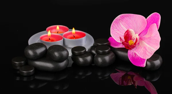 Σπα πέτρες με ορχιδέα λουλούδι και κεριά που απομονώνονται σε μαύρο — Φωτογραφία Αρχείου