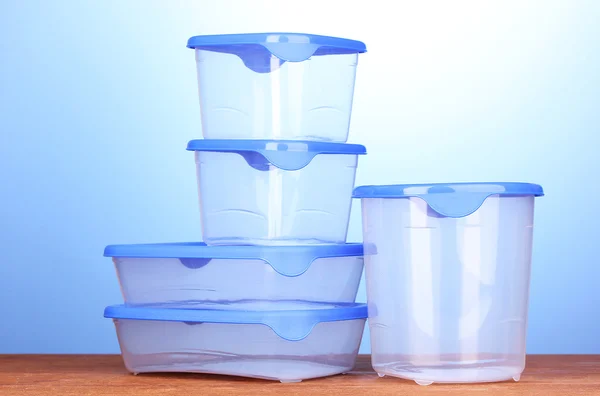 Recipientes de plástico para alimentos em mesa de madeira em fundo azul — Fotografia de Stock