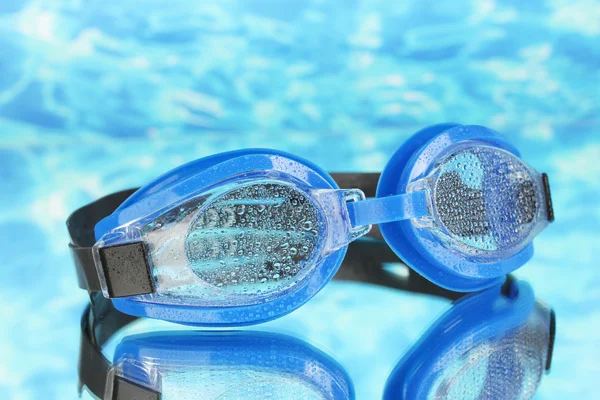 Gafas de baño azul con gotas sobre fondo marino azul —  Fotos de Stock