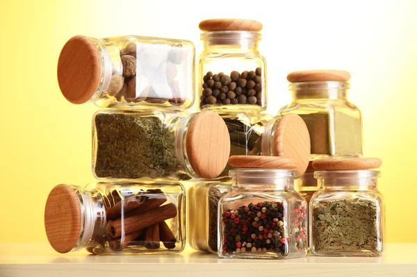 Pulver kryddor i glasburkar på gul bakgrund — Stockfoto