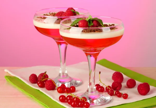 Gelatina di frutta con bacche in bicchieri su tavolo di legno su sfondo rosa — Foto Stock