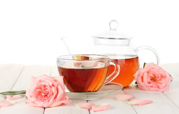 Tetera y taza de té con rosas sobre mesa de madera blanca — Foto de Stock