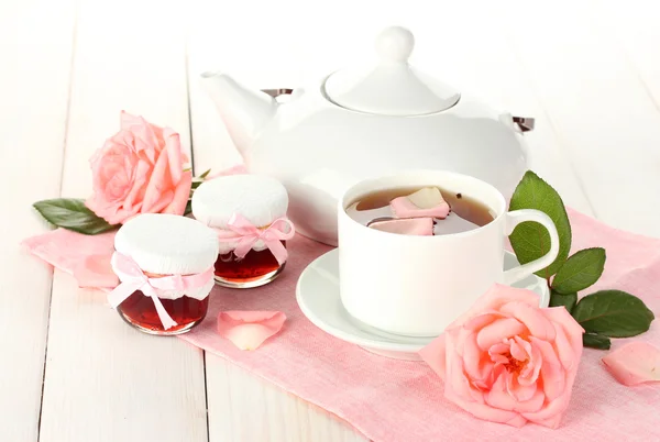 Teekanne und Tasse Tee mit Rosen und Marmelade auf weißem Holztisch — Stockfoto