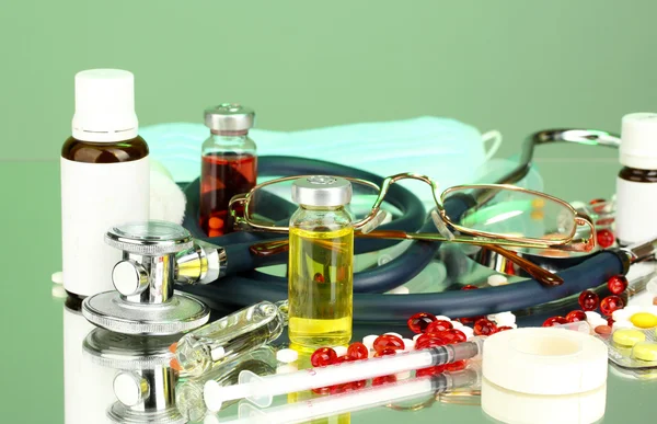 Medicines and a stethoscope on a green background close-up — Stock Photo, Image