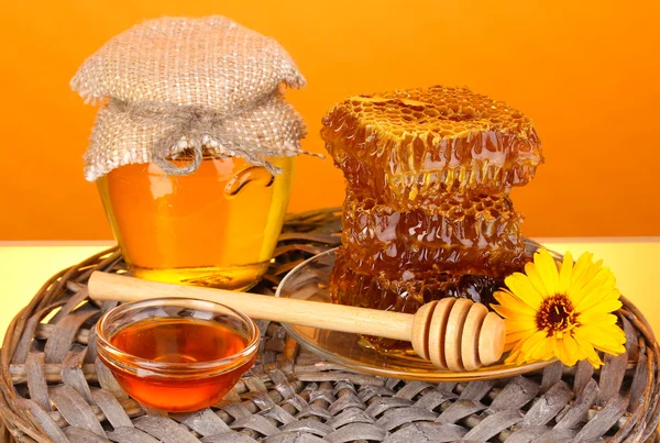 Pot met honing en honingraat op oranje achtergrond — Stockfoto
