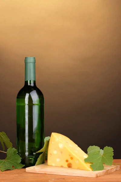 Bottle of great wine and cheese on wooden table on brown background — Stock Photo, Image