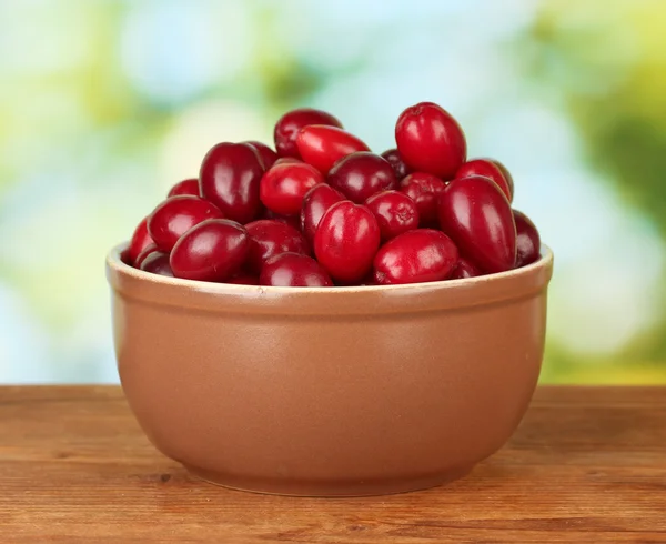 Fresh cornel berries in ceramical bowl on green background close-up — Stock Photo, Image