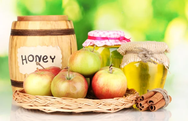 Honey and apples with cinnamon on wicker cradle on natural background — Stock Photo, Image